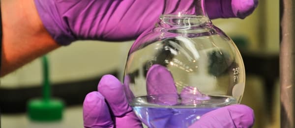 Round glass container with clear fuel at the bottom